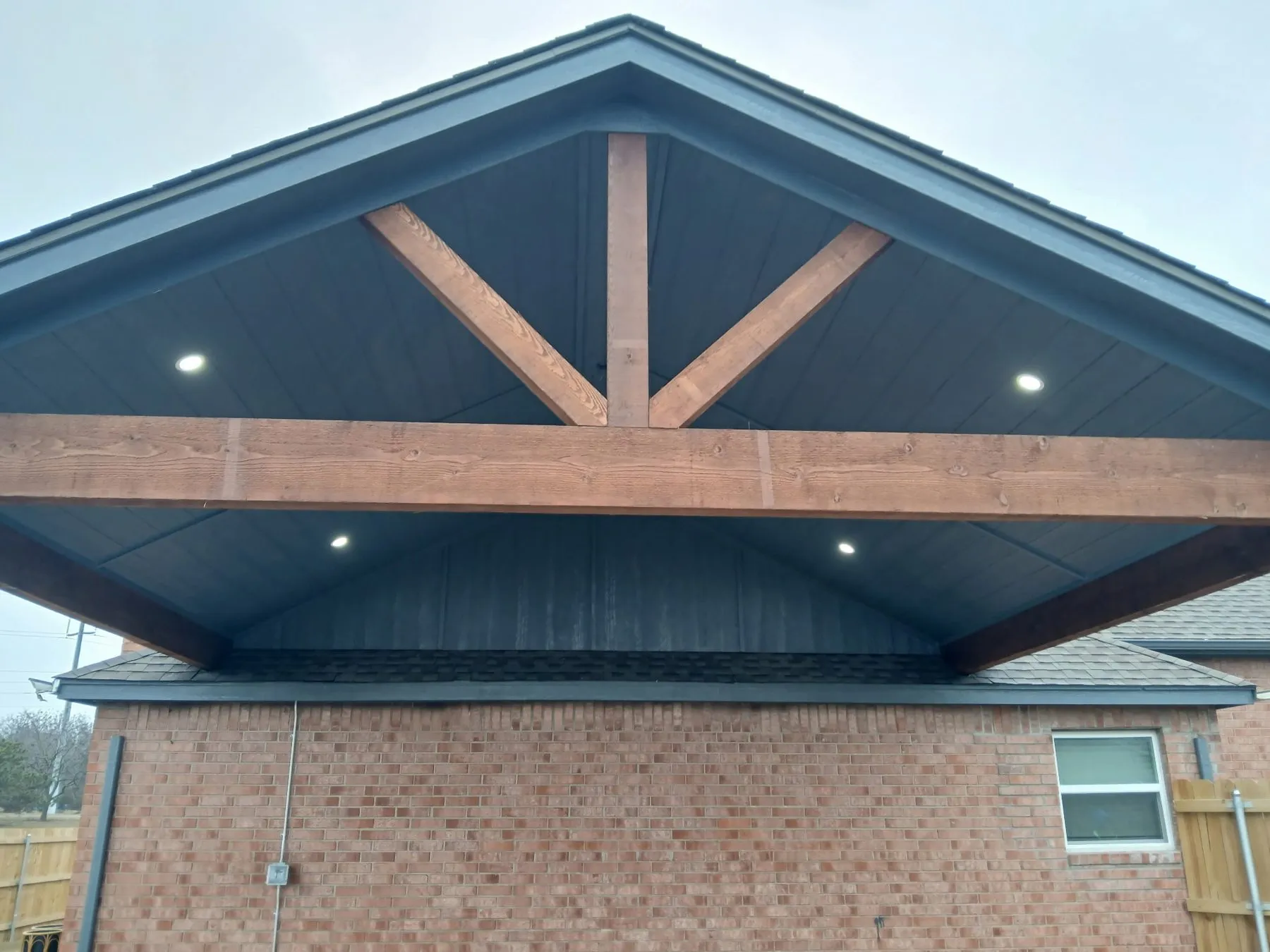 Stained cedar posts, exposed beams and wood plank ceiling on an extended gable-roof porch in Collinsville