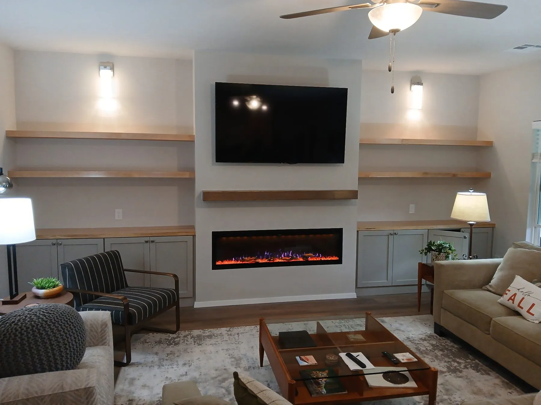 Finished fireplace bump-out with cabinets and floating built-in shelves on both sides in a Bixby living room